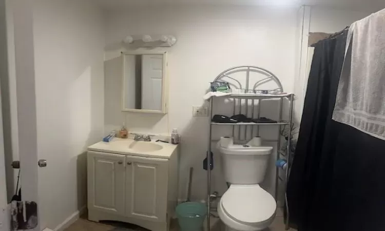 Bathroom featuring tile patterned floors, toilet, curtained shower, and vanity