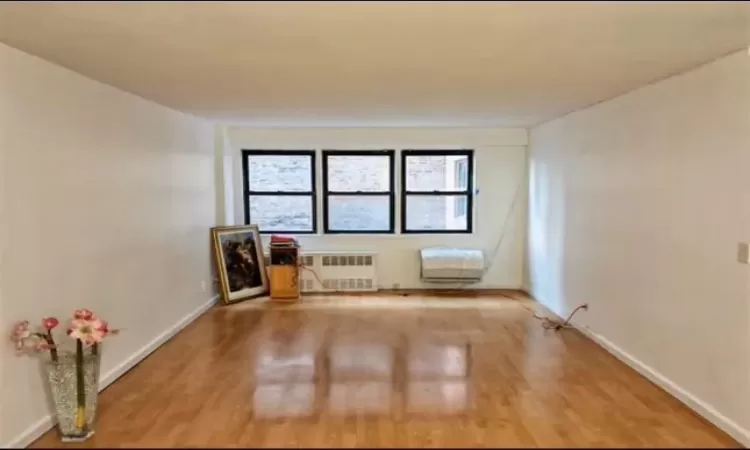 Unfurnished room with radiator heating unit and wood-type flooring