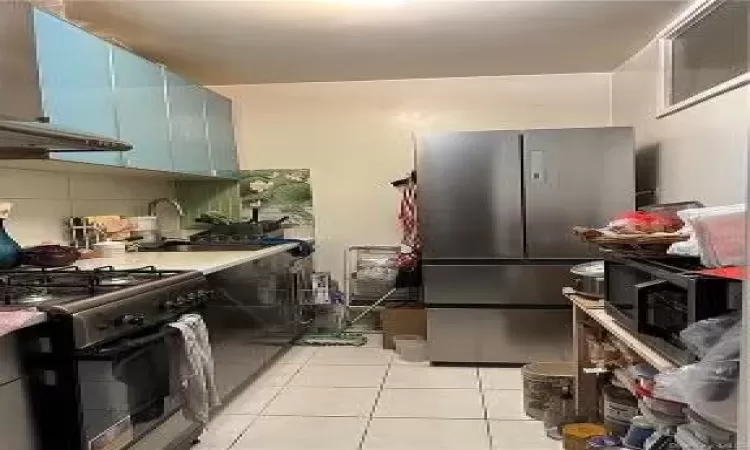 Kitchen featuring appliances with stainless steel finishes, backsplash, extractor fan, sink, and light tile patterned flooring