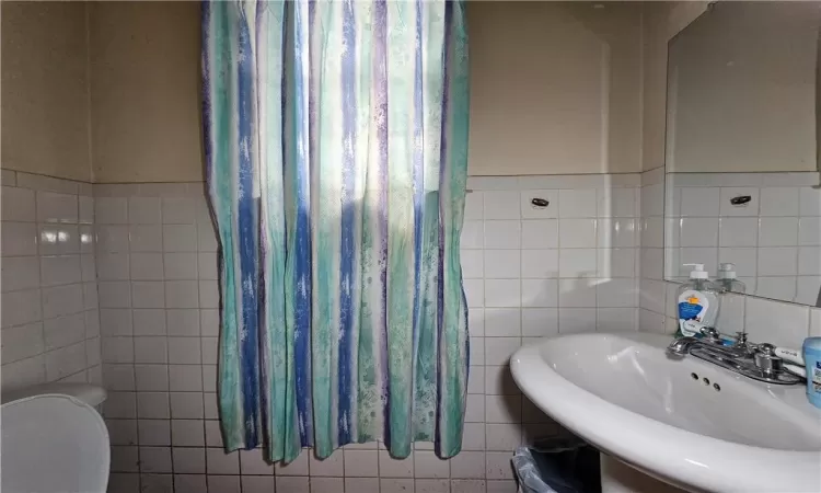 Bathroom featuring tile walls, sink, and toilet