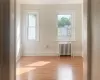 Empty room with radiator heating unit, light wood-type flooring, and a healthy amount of sunlight