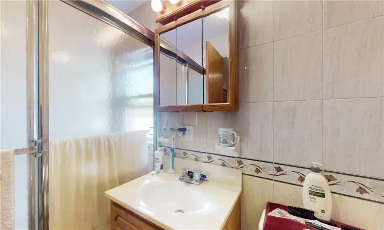 Bathroom 2 unit 2 featuring tile walls, vanity, and a shower with shower door