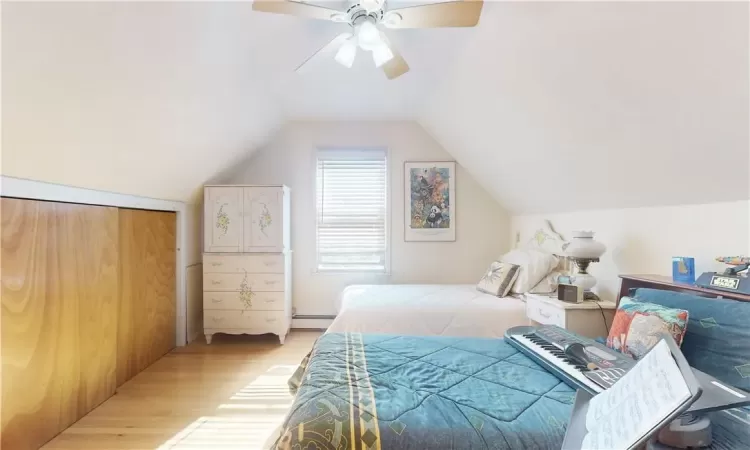 Bedroom 4 unit 2 with ceiling fan, lofted ceiling, hardwood flooring, a closet, and a baseboard radiator