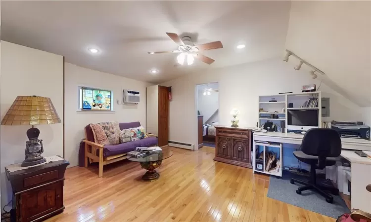 Home office with ceiling fan, a wall mounted AC, a baseboard heating unit, rail lighting, and light wood flooring