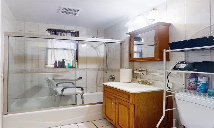 Full bathroom unit 1 with enclosed tub / shower combo, toilet, tile patterned floors, tile walls, and vanity