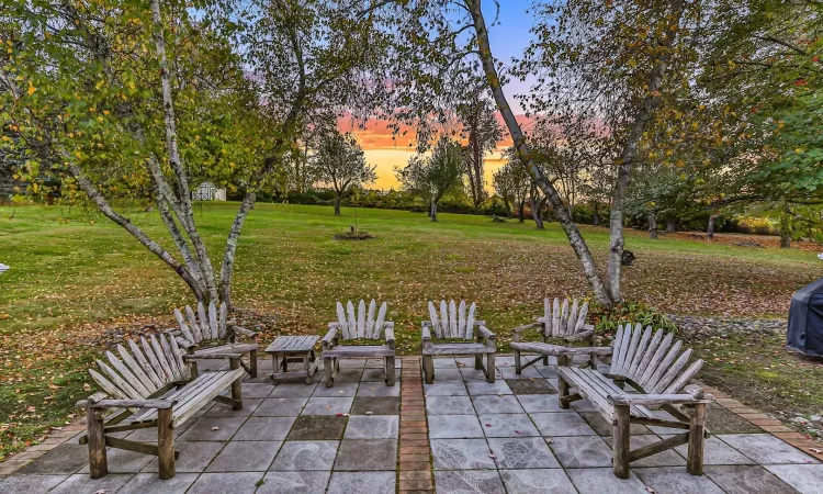 Patio terrace at dusk featuring a lawn