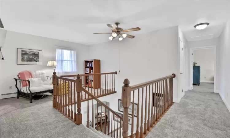 Hallway featuring light colored carpet and baseboard heating