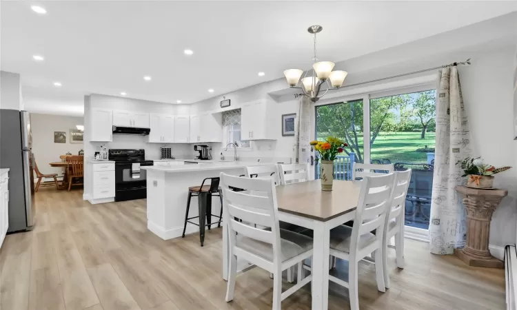 Dining space with a notable chandelier, light wood-type flooring, sink, and a baseboard heating unit