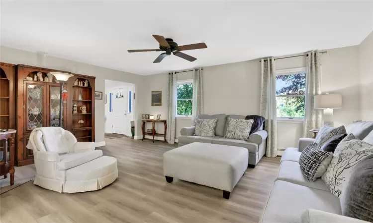 Living room featuring ceiling fan, a healthy amount of sunlight, light wood-type flooring, and a baseboard radiator