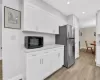 Kitchen featuring white cabinets, light hardwood / wood-style floors, and stainless steel refrigerator