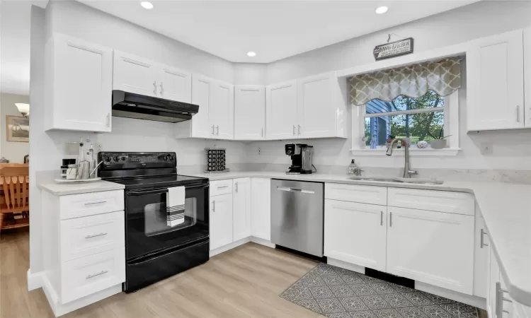 Kitchen with dishwasher, electric range, white cabinetry, and sink