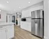 Kitchen with light stone countertops, white cabinetry, stainless steel refrigerator, and light hardwood / wood-style flooring