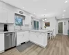 Kitchen featuring stainless steel dishwasher, white cabinets, light wood-type flooring, and sink