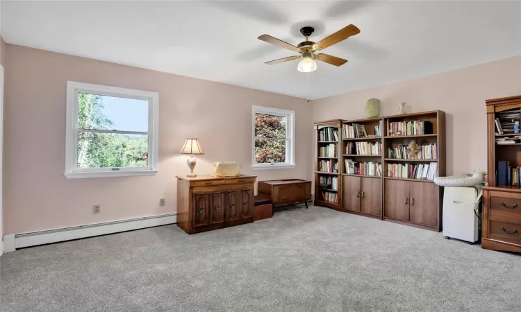 Living area featuring light carpet, a baseboard radiator, and ceiling fan