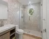 Bathroom featuring backsplash, vanity, a shower with shower door, and toilet