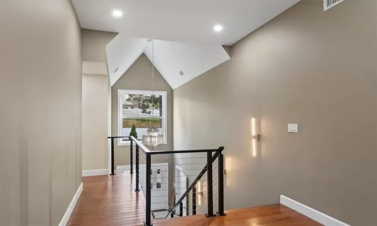 Stairway featuring high vaulted ceiling and hardwood / wood-style floors