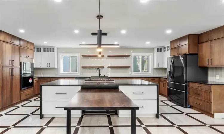 Kitchen featuring white cabinets, stainless steel appliances, hanging light fixtures, and a kitchen island