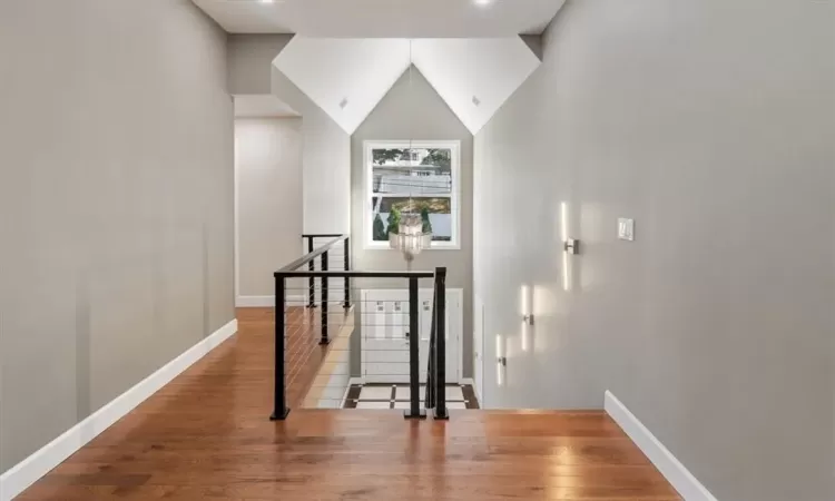 Corridor featuring hardwood / wood-style flooring, a notable chandelier, and high vaulted ceiling