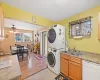 Laundry area with light wood-type flooring, ceiling fan, sink, stacked washer / drying machine, and a baseboard radiator