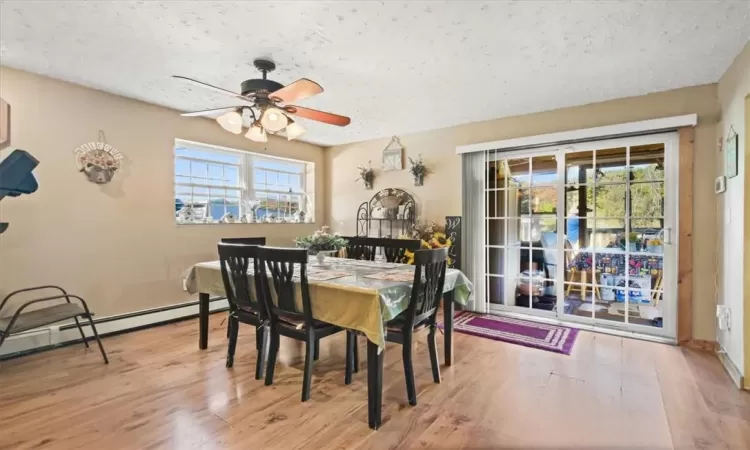 Dining space featuring ceiling fan, hardwood / wood-style flooring, a baseboard radiator, and a textured ceiling