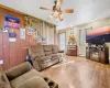 Living room with wood walls, baseboard heating, hardwood / wood-style flooring, and ceiling fan