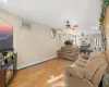 Living room with light wood-type flooring, ceiling fan, a baseboard heating unit, and a wall mounted AC