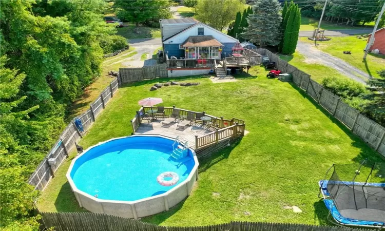 View of swimming pool with a trampoline, a wooden deck, and a lawn