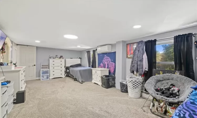 Bedroom featuring light colored carpet and a wall unit AC