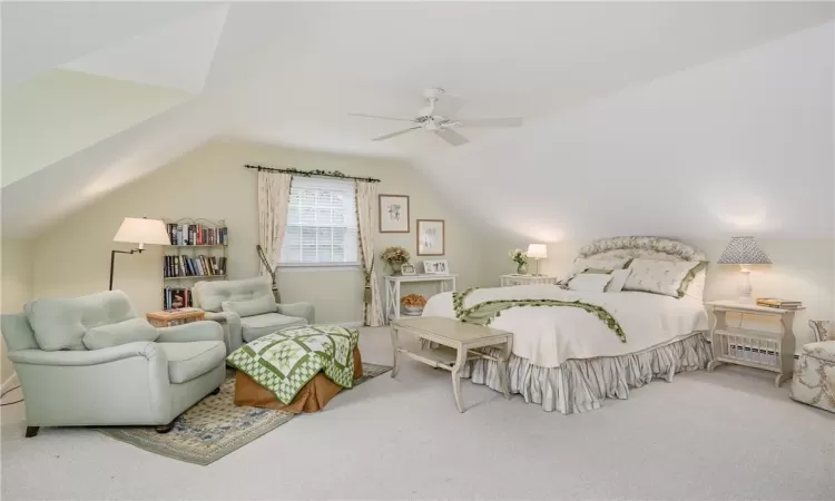 Carpeted bedroom with ceiling fan, a baseboard radiator, and lofted ceiling