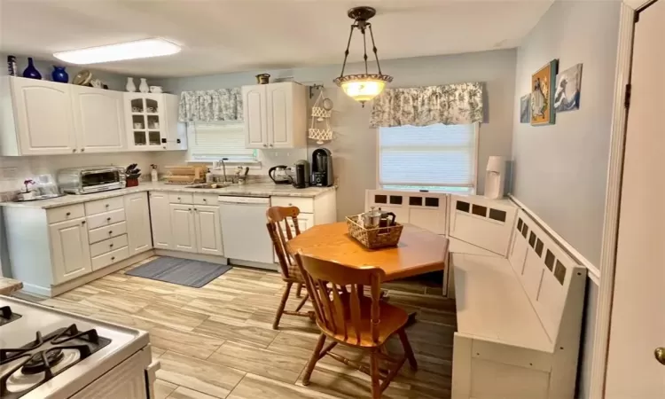 Kitchen with white appliances, plenty of natural light, hanging light fixtures, and white cabinets