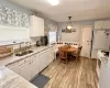 Kitchen featuring white cabinets, hanging light fixtures, sink, white appliances, and light wood-type flooring