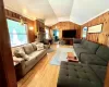 Living room with crown molding, vaulted ceiling, hardwood / wood-style flooring, and wooden walls