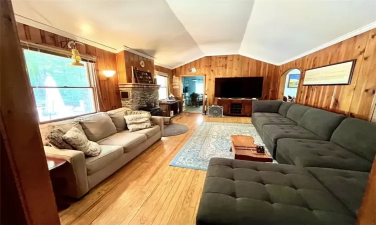 Living room with crown molding, vaulted ceiling, hardwood / wood-style flooring, and wooden walls