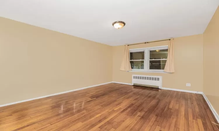 Empty room with hardwood / wood-style flooring and radiator