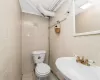 Bathroom featuring tile patterned flooring, sink, toilet, and tile walls