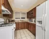 Kitchen featuring white appliances, backsplash, sink, and light tile patterned floors