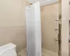 Bathroom with toilet, tile walls, and walk in shower