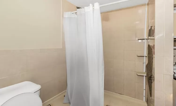 Bathroom with toilet, tile walls, and walk in shower