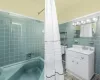 Bathroom with shower / tub combo with curtain, tile walls, and vanity