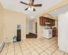 Kitchen featuring white appliances, a baseboard heating unit, light tile patterned floors, and ceiling fan