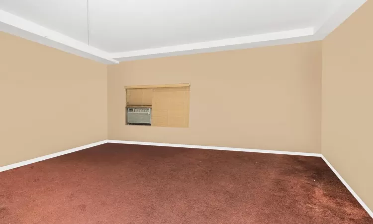 Carpeted spare room with a raised ceiling and cooling unit