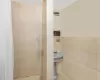 Bathroom featuring walk in shower and tile walls