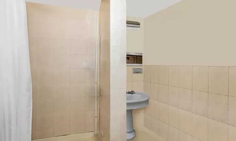 Bathroom featuring walk in shower and tile walls