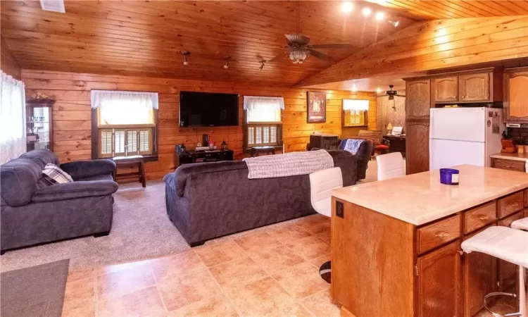 Living room featuring ceiling fan, lofted ceiling, wood walls, and wood ceiling