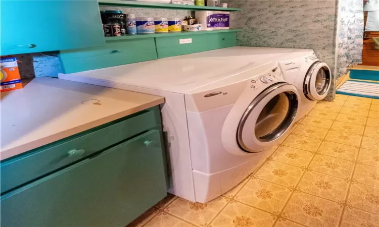 Laundry area in upstairs full bath with washer and clothes dryer and cabinets