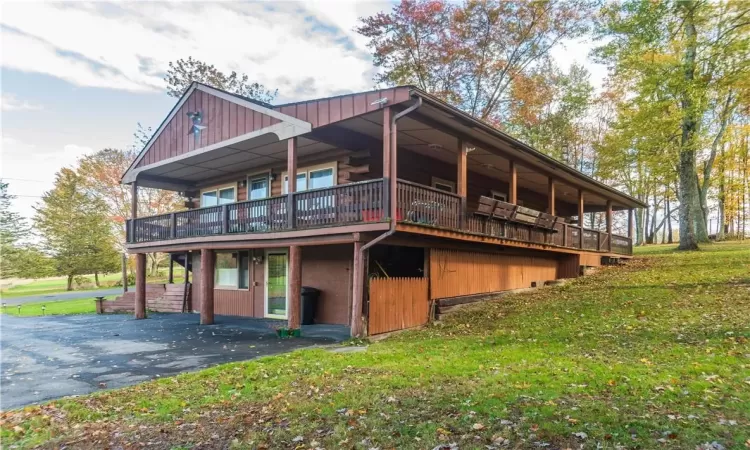 View of property exterior with a wooden deck and a lawn