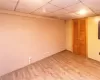 Lower level bedroom used as a transitional room featuring a drop ceiling and hardwood / wood-style flooring