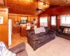 Carpeted living room featuring wood walls, ceiling fan, wooden ceiling, vaulted ceiling, and sink