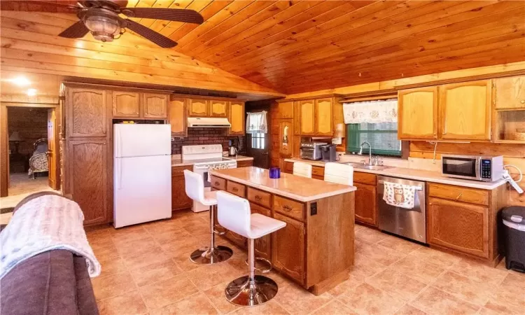 Kitchen with wooden ceiling, a kitchen island, vaulted ceiling, sink, and appliances with stainless steel finishes