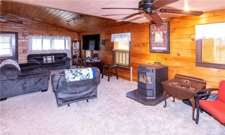 Carpeted living room featuring a lofted ceiling, wooden walls, and wood ceiling